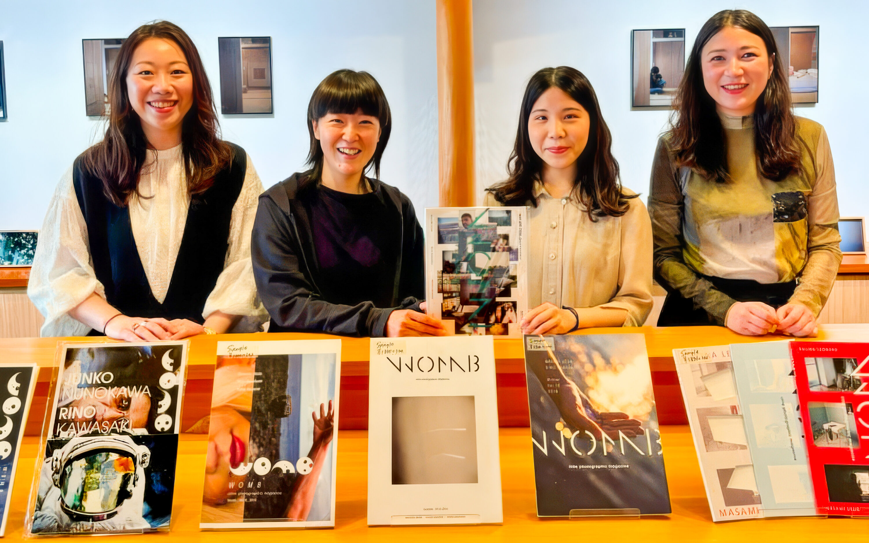 WOMB photographers Masami Ueda, Rino Kawasaki, Sana Kohmoto, and Kalina Leonard in front of the exhibit of WOMB magazines and photo books at their 10th anniversary exhibition at the Kyoto Museum of Photography